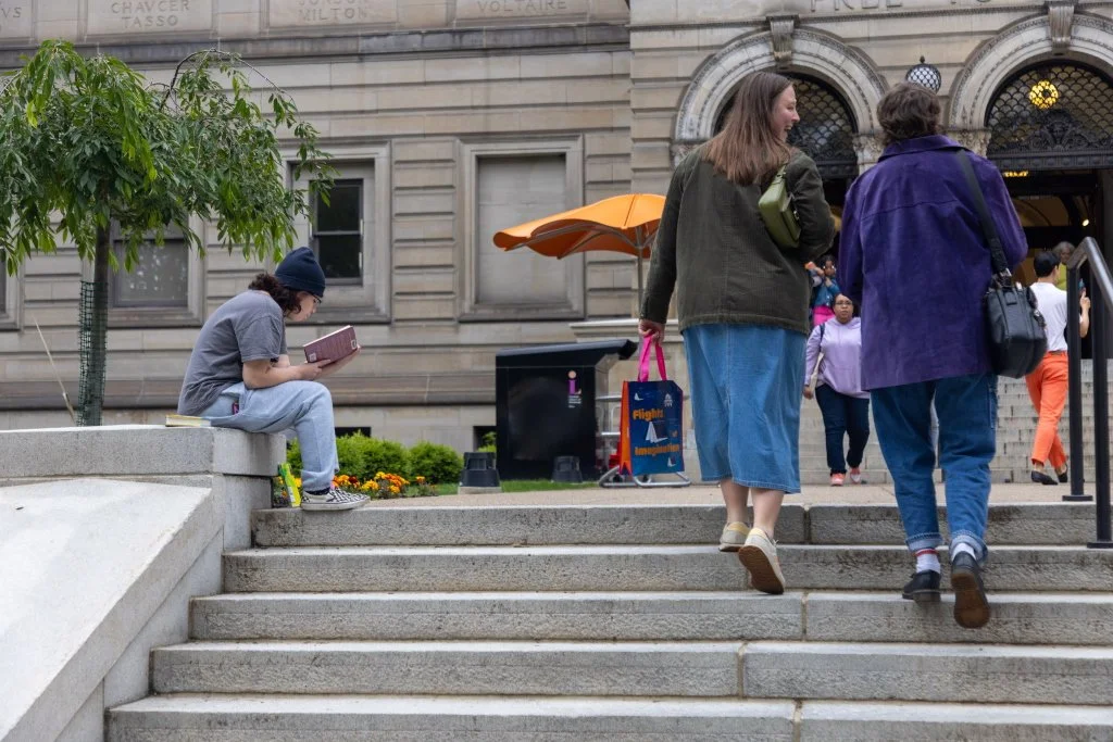 person reading on the steps of Carnegie Library of Pittsburgh main/Oakland branch